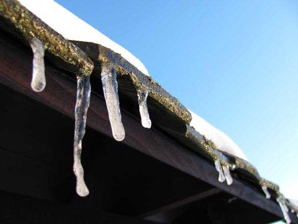 Eiszapfen hängen an einem Dach herunter