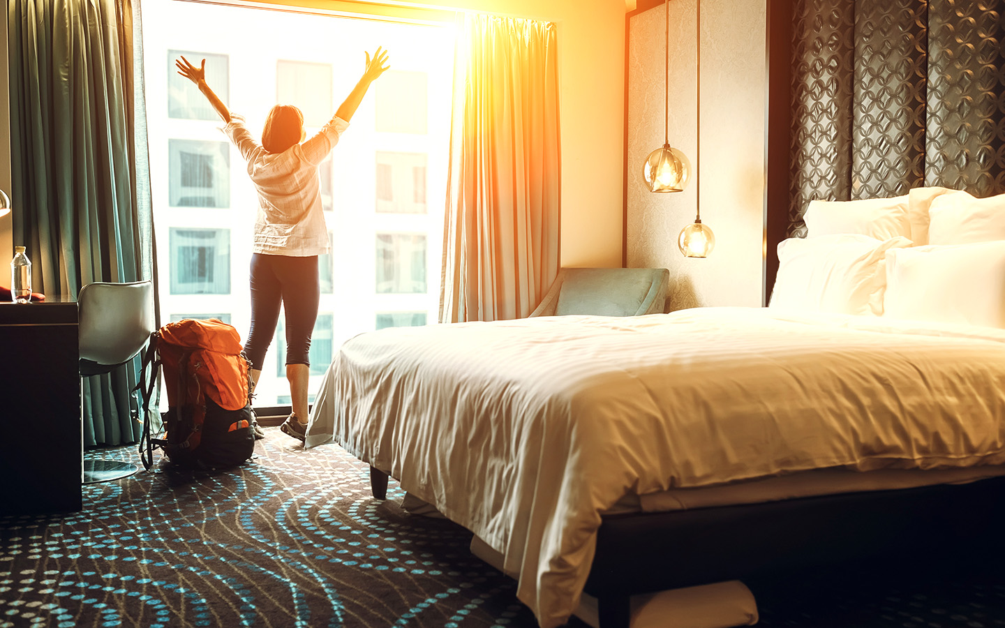 Frau freut sich über ihr Hotelzimmer im Luxushotel