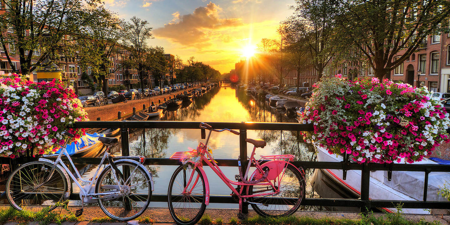 Amsterdam im Sonnenaufgang auf der Brücke mit Fahrrädern und Blumen, Niederlande