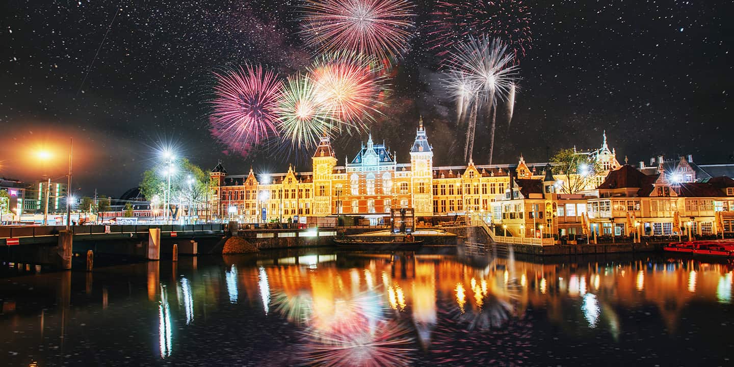 Amsterdam zum Jahreswechsel mit farbigen Feuerwerken auf schwarzem Hintergrund