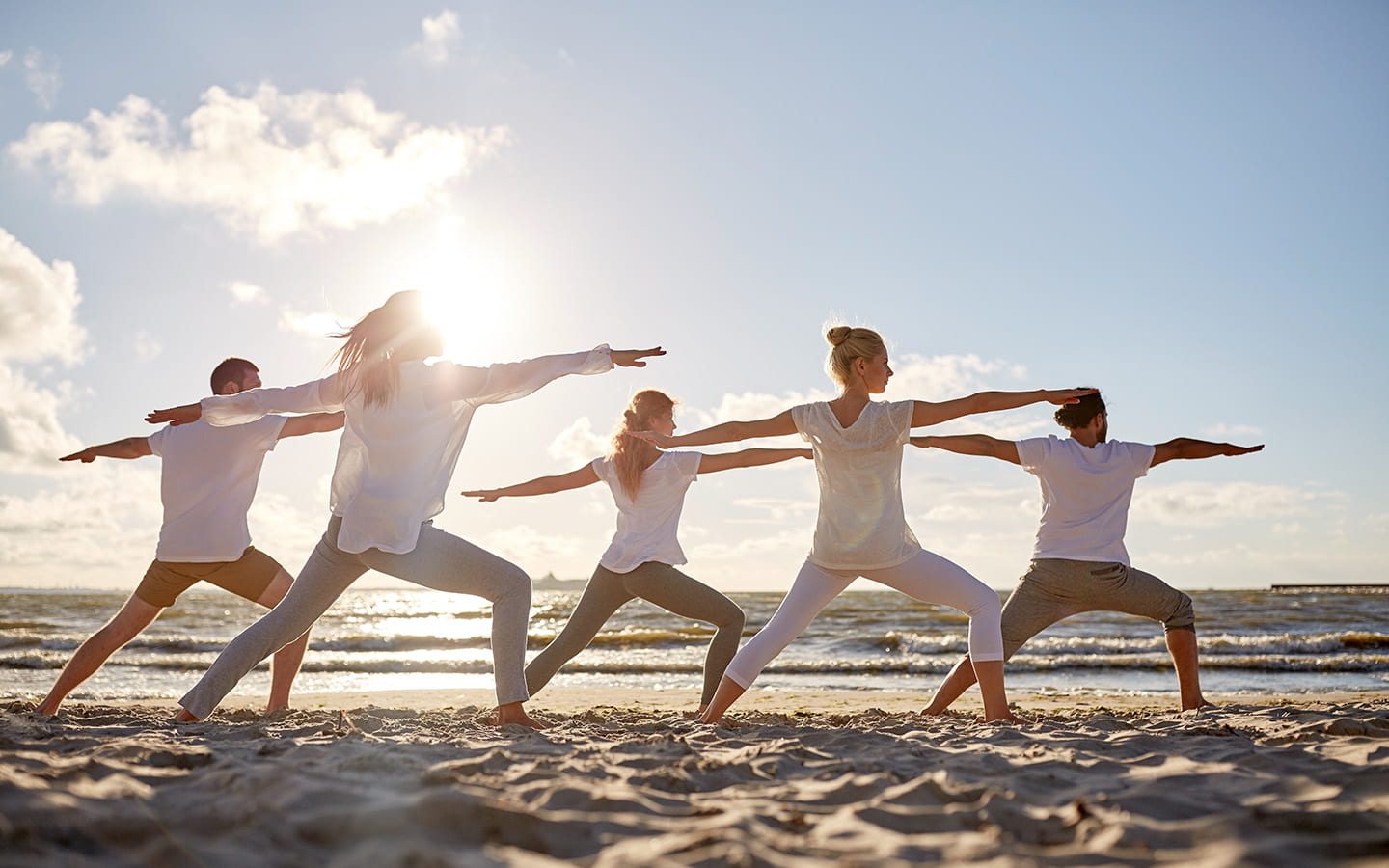 Gruppe junger Frauen praktiziert Yoga am Sandstrand an der Ostsee im Sommer