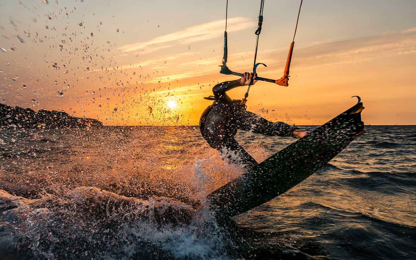 Kitesurfer auf den Wellen der Ostsee im Sonnenuntergang