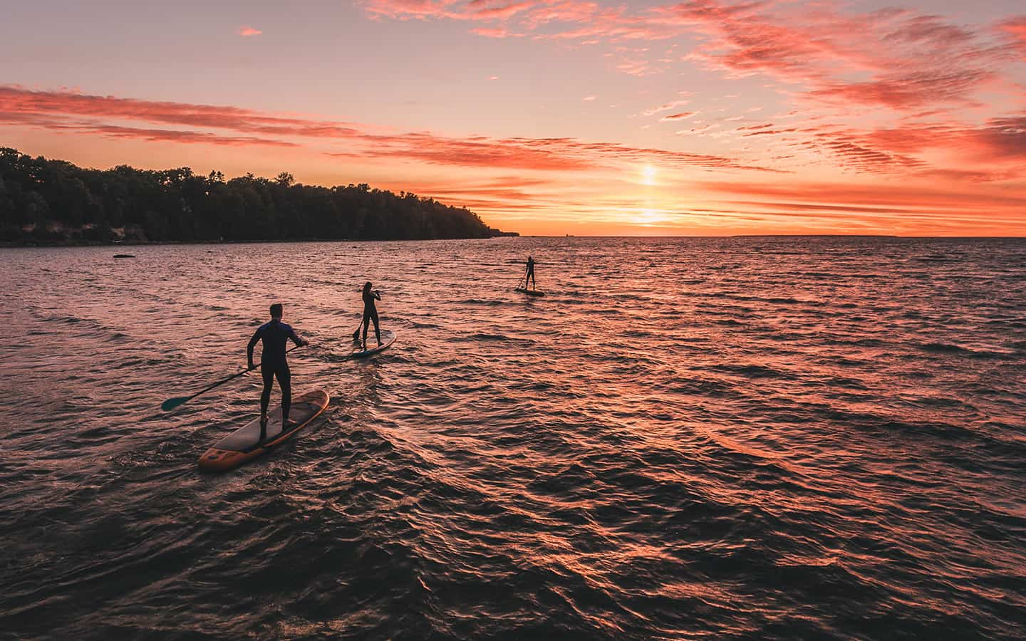 Reisegruppe beim Stand Up Paddling im Sonnenuntergang