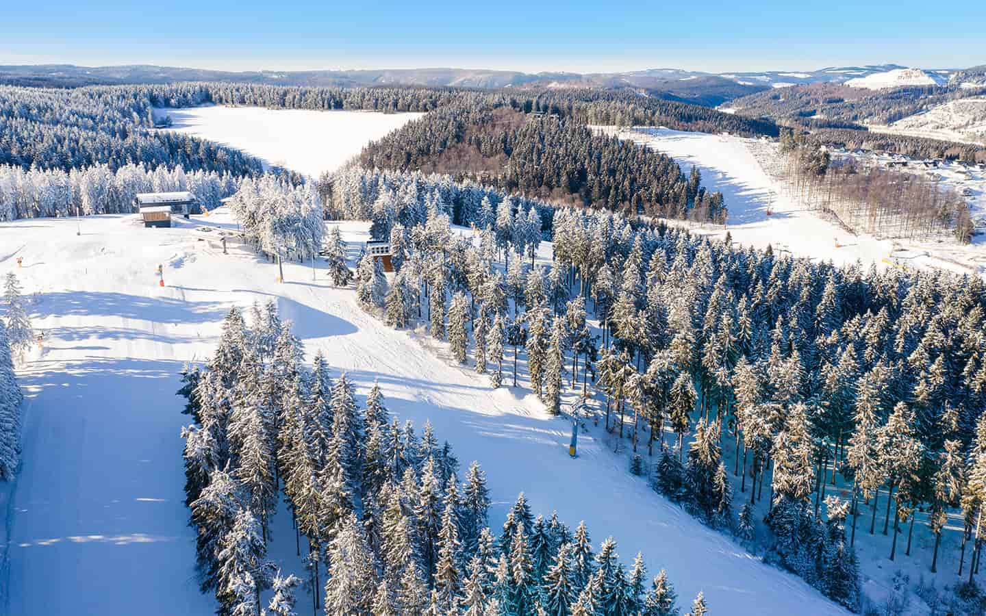 Luftbild auf den Wintersportpisten beim Skilift Winterberg. Schlittenpisten und Skipisten zwischen schneebedeckten Fichtenwäldern